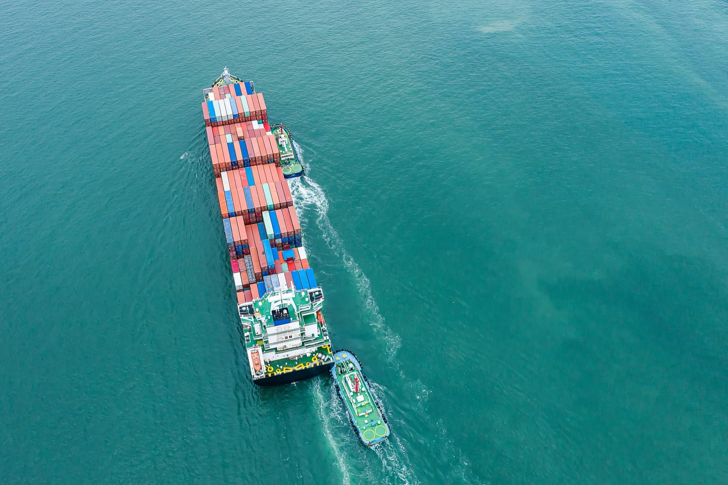 Aerial view of a container ship under tug escort