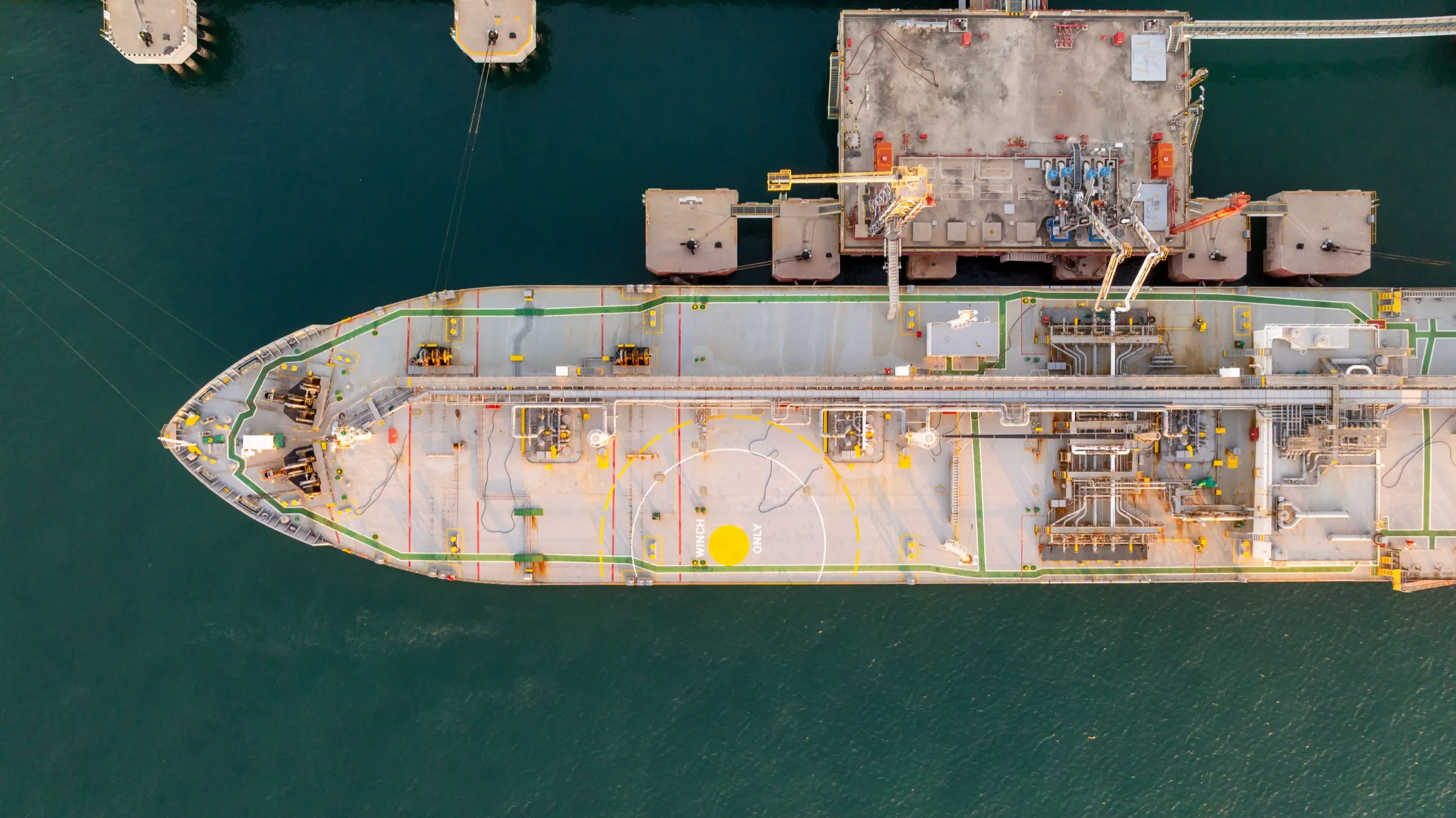 Tanker vessel alongside a terminal, aerial top view