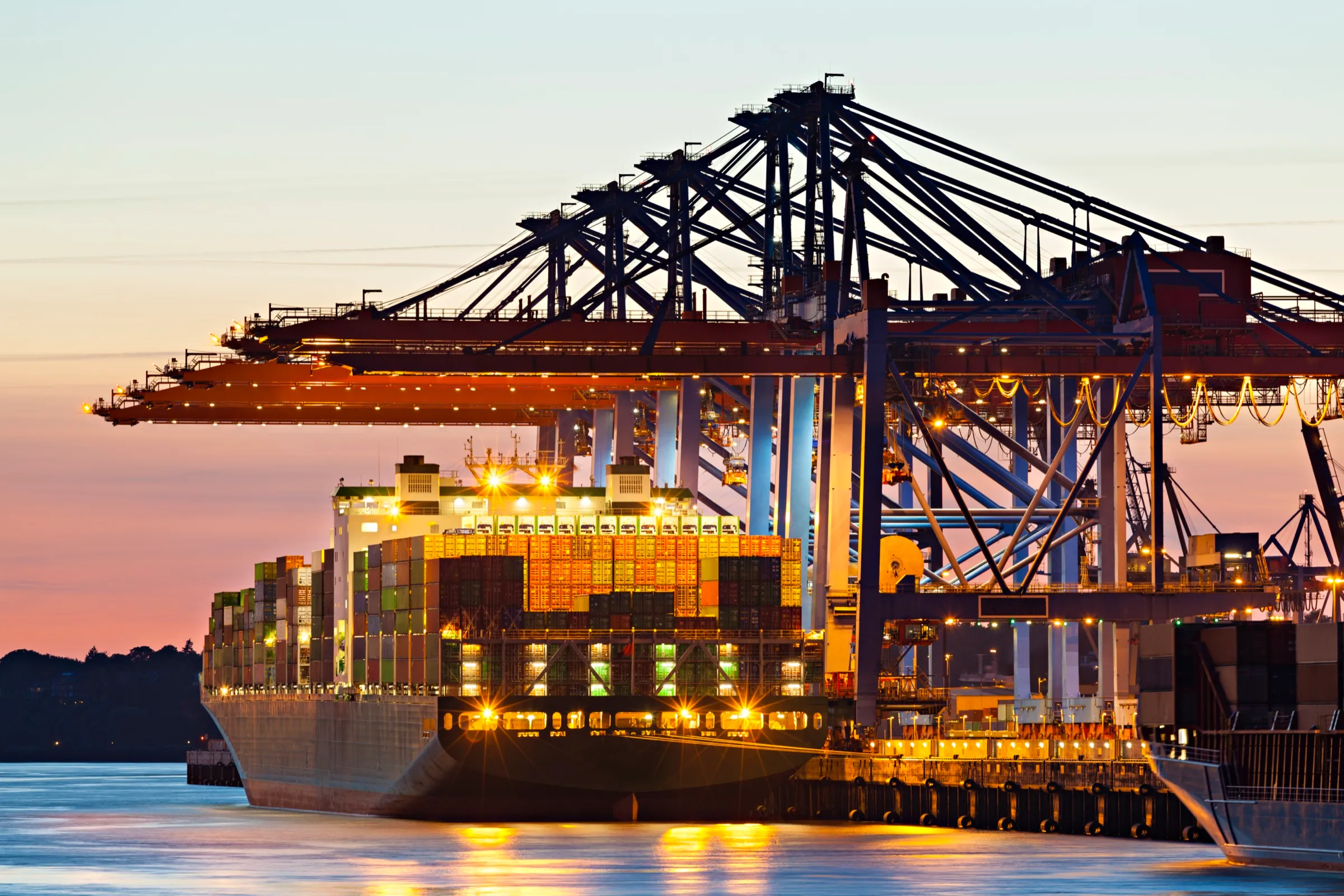 Container terminal illuminated at night with vessel alongside under gantry cranes