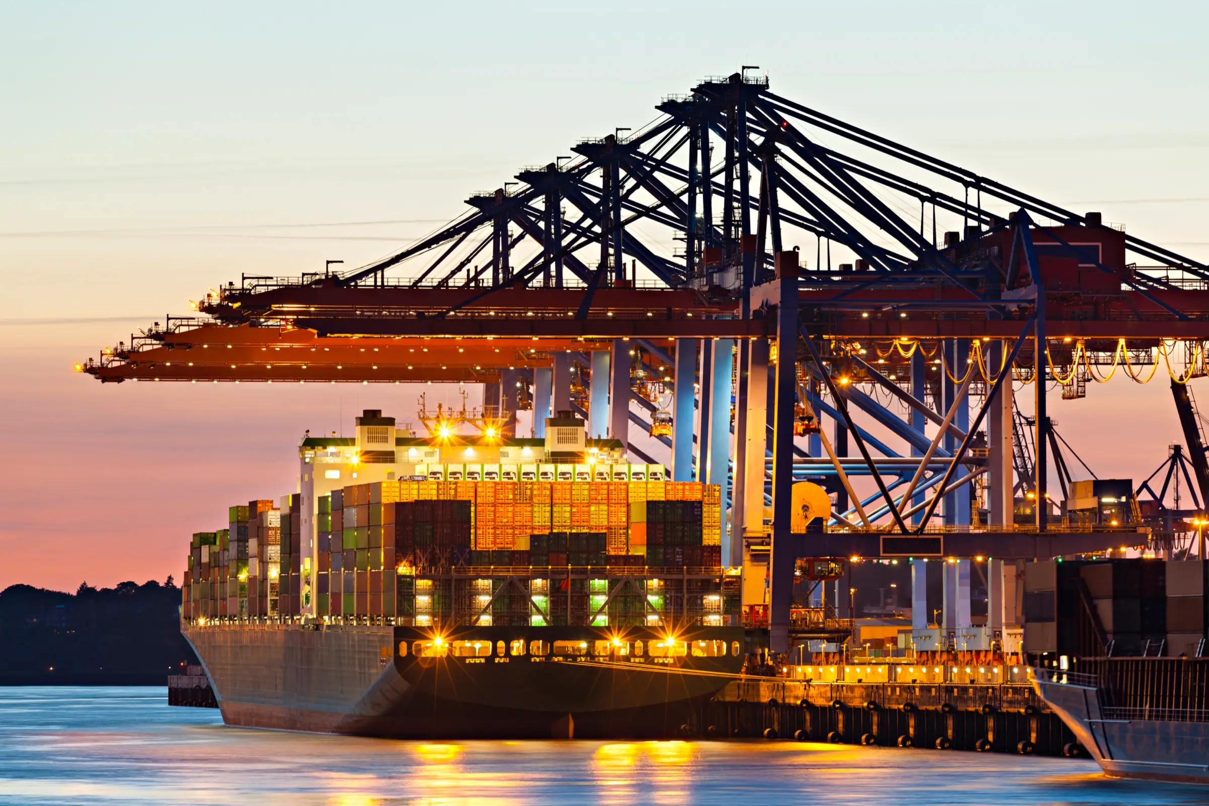 Container terminal illuminated at night with vessel alongside under gantry cranes